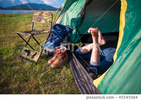 Close up of woman legs relaxing in camping tent with mountain la Close up of woman legs relaxing in camping tent with mountain la 45545084