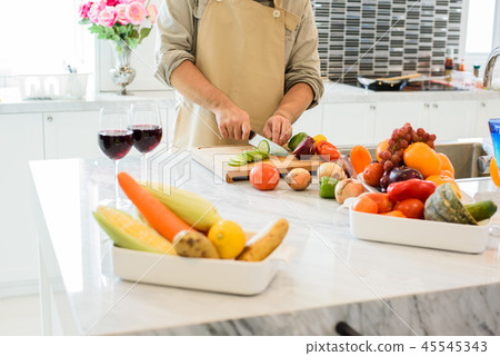 Man cooking and slicing vegetable in the kitchen Man cooking and slicing vegetable in the kitchen 45545343