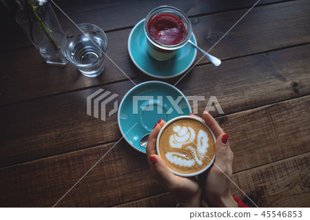 Female hands holding a Cup of coffee an dessert on wooden table Female hands holding a Cup of coffee an dessert on wooden table 45546853