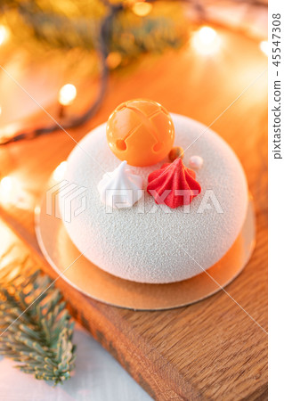 Mini mousse pastry dessert covered with white velour. Garland lamps bokeh on background. Modern 45547308