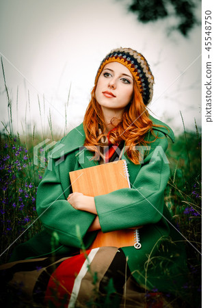 girl holding notebook and sitting at gren grass 45548750