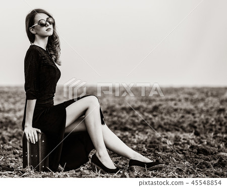woman sitting on suitcase at countryside woman sitting on suitcase at countryside 45548854