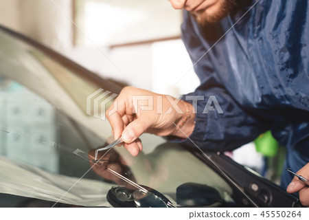 Close up Car glaze worker fixing and repairing a windshield or windshield of a car at a garage Close up Car glaze worker fixing and repairing a windshield or windshield of a car at a garage 45550264