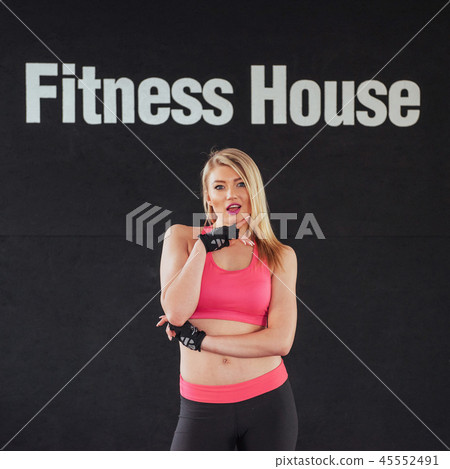 Sexy girl in sportswear with a smile posing for the camera in a sports hall Sexy girl in sportswear with a smile posing for the camera in a sports hall 45552491