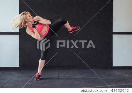 boxer woman giving kick in the gym on black white background 45552942