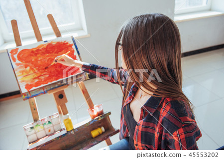 Pretty Pretty Girl artist paints on canvas painting on the easel Pretty Pretty Girl artist paints on canvas painting on the easel 45553202