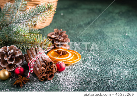 Cinnamon sticks, fir branches and dry oranges on dark green background. Christmas greeting card Cinnamon sticks, fir branches and dry oranges on dark green background. Christmas greeting card 45553269