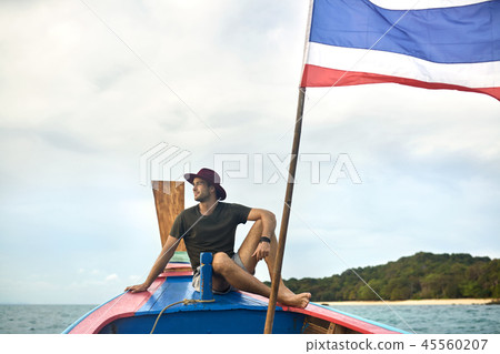 Cheerful man with stubble is sailing on colorful boat 45560207
