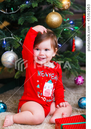 Christmas photo of infant in red cap. New Year's holidays and Christmas tree. Christmas photo of infant in red cap. New Year's holidays and Christmas tree. 45561063