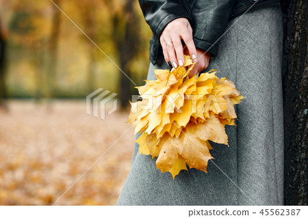 Woman with yellow leaves stand in autumn city park Woman with yellow leaves stand in autumn city park 45562387