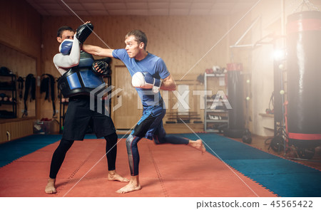 Male kickboxer in gloves practicing hand punch Male kickboxer in gloves practicing hand punch 45565422