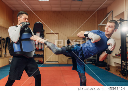 Kickboxer practicing kicking with personal trainer Kickboxer practicing kicking with personal trainer 45565424