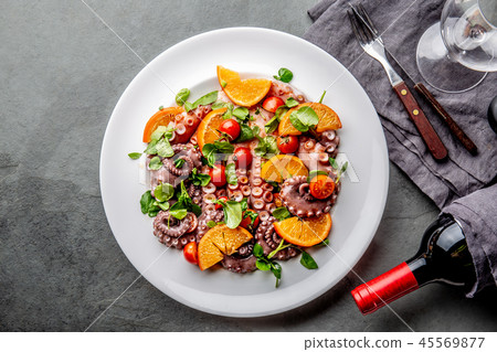 Whole octopus salad with orange, tomatoes and cress salad on white plate. Top view Whole octopus salad with orange, tomatoes and cress salad on white plate. Top view 45569877