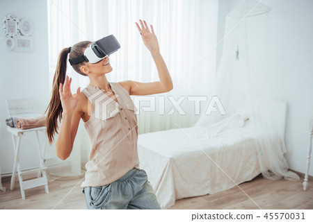 woman gets experience of using VR-glasses virtual reality headset in a bright studio 45570031