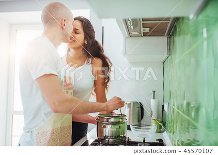 Happy young couple preparing on the stove Happy young couple preparing on the stove 45570107