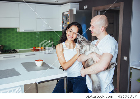 Happy young beautiful couple sitting at kitchen cat smiling. Happy young beautiful couple sitting at kitchen cat smiling. 45570317