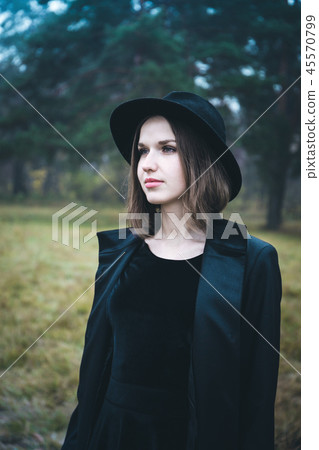 Portrait of a girl in a black hat in the gloomy forest Portrait of a girl in a black hat in the gloomy forest 45570799