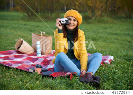 Autumn photo of a woman who sits on a blanket Autumn photo of a woman who sits on a blanket 45572984