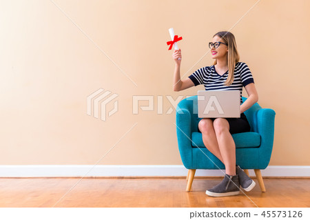Young woman holding a diploma and her laptop 45573126
