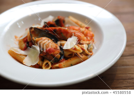 Penne pasta tomato sauce arabiata with seafood on wood background vintage style 45580558