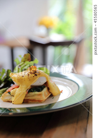 Breakfast food egg benedict , poached egg with yellow sauce with waffle and smoked salmon on wood background 45580565