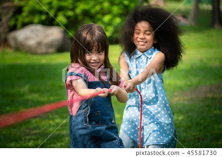 Happy children playing tug of war in the park. Happy children playing tug of war in the park. 45581730