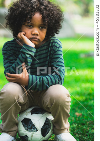 Unhappy little african american kid in the park. 45581832