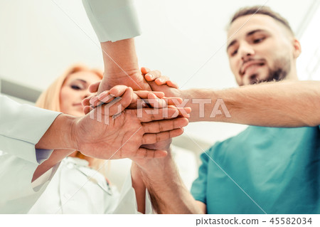 Doctor, surgeon and nurse join hands together. Doctor, surgeon and nurse join hands together. 45582034