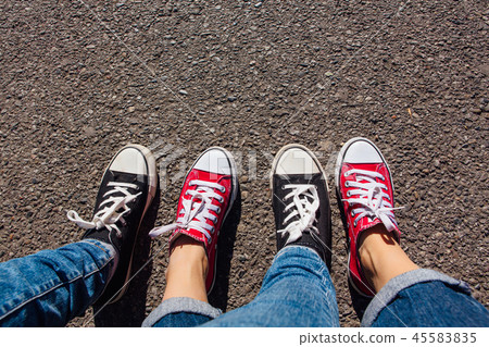 Red and black sneakers shoes on women's feet. Red and black sneakers shoes on women's feet. 45583835