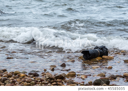 DSLR camera on beach wet from water sea wave DSLR camera on beach wet from water sea wave 45585035