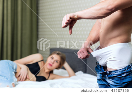 Young man looking in underpants and shows thumbs down gesture. 45587566