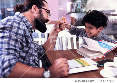 Cheerful cute dark-eyed son feeling amazing having fun with his father 45587808