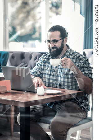 Bearded freelancer writer working on his laptop having coffee Bearded freelancer writer working on his laptop having coffee 45588201