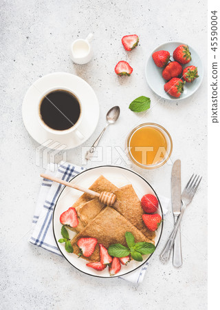 Crepes or blini with honey, strawberries and cup of coffee 45590004