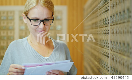 Portrait of a young stylish woman with a bundle of letters in her hands in the post office 45590445