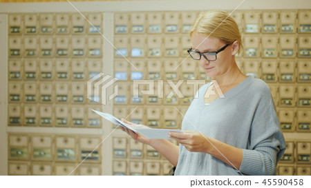 A woman looks at the letters just received. It should be in the post office on the background of A woman looks at the letters just received. It should be in the post office on the background of 45590458