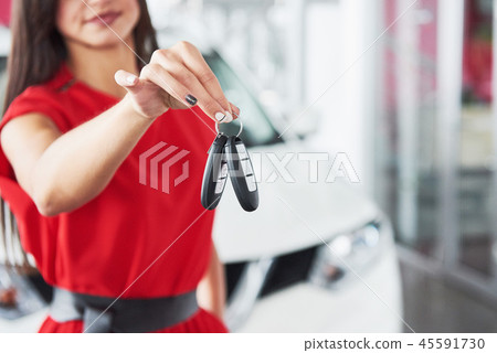 Smiling car salesman handing over your new car keys, dealership and sales concept. Happy girl the Smiling car salesman handing over your new car keys, dealership and sales concept. Happy girl the 45591730