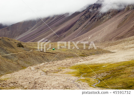 A small house stands among the high mountains. A small house stands among the high mountains. 45591732
