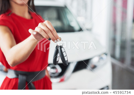 Smiling car salesman handing over your new car keys, dealership and sales concept. Happy girl the Smiling car salesman handing over your new car keys, dealership and sales concept. Happy girl the 45591734