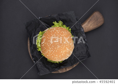 Big hamburger with sesame seeds on a black background. Fast food and free space for text. View from 45592401