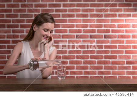 Woman pouring water from bottle into glass  45593414