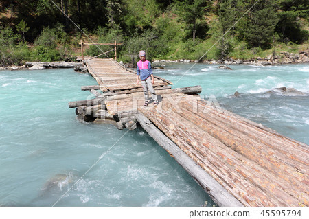 Girl tourist walking along a wooden bridge  45595794