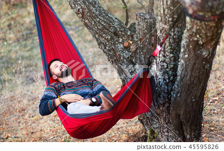 Man relaxing in a hammock on a picnic Man relaxing in a hammock on a picnic 45595826