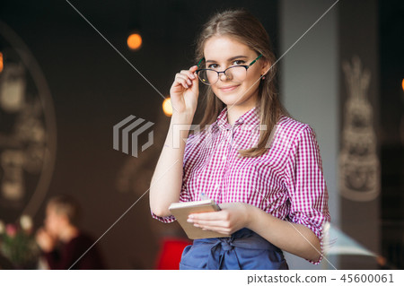 Portrait of a beautiful friendly waitress in glasses with notepapers and pen ready to take your Portrait of a beautiful friendly waitress in glasses with notepapers and pen ready to take your 45600061