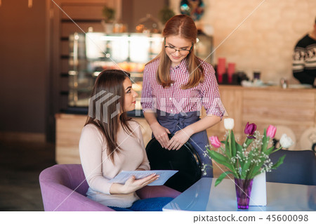 Hospitable waitress help to customer what to choose something from menu Hospitable waitress help to customer what to choose something from menu 45600098