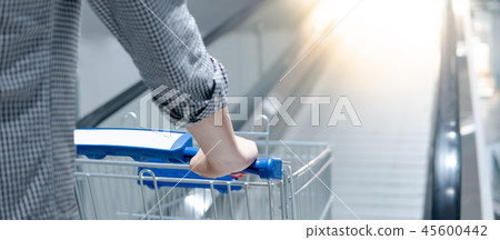 Male hand holding shopping cart on travelator 45600442