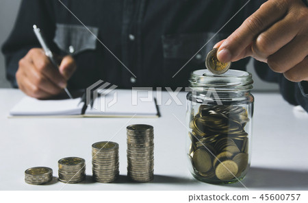 Hand drop a coin with money coin stack growing Hand drop a coin with money coin stack growing 45600757
