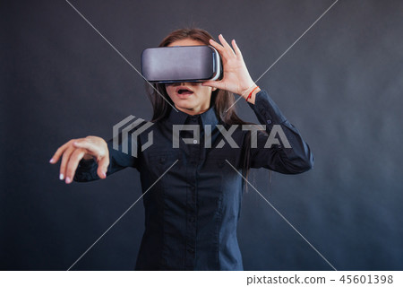 Happy woman on a black background in the studio gets the experience of using VR-glasses virtual 45601398