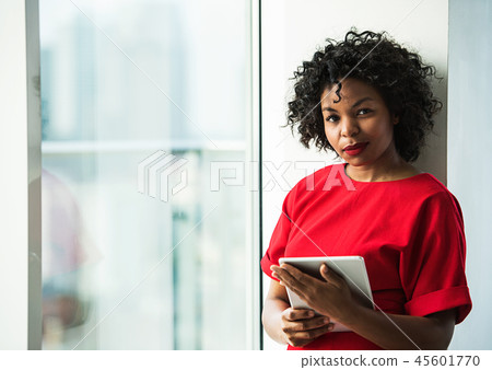A woman with tablet standing by the window against London panorama. 45601770