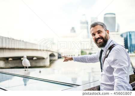 Hipster businessman standing by the river in London, pointing at seagull. Hipster businessman standing by the river in London, pointing at seagull. 45601807